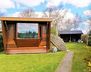 Vakantiepark De Koorn-aar - Chalet 102 type C in De Dennen, Texel met groene tuin en houten buitenkant.