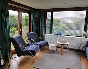 Gezellige zithoek in Vakantiepark De Koorn-aar - Chalet 102 type C, De Dennen, Texel, met ruime ramen en comfortabele stoelen.