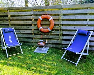 Tuin met ligstoelen en barbecue bij Vakantiepark De Koorn-aar - Chalet 102 type C, De Dennen, Texel.