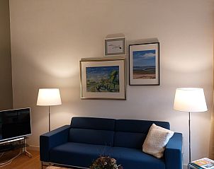 Gezellige woonkamer van De Uithof vakantiehuis in De Dennen, Texel, met comfortabele bank en kunst aan de muur.