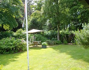 Ruime tuin van De Uithof vakantiehuis, De Dennen, Texel, met zitgedeelte en groene omgeving.