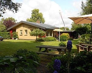 Buitenzijde van De Uithof bungalow in De Dennen, Texel, omgeven door weelderige natuur.