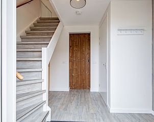 Inkomhal van Wulpenweid 10 de Wulp, vakantiehuis De Dennen Texel met houten trap en kapstok.