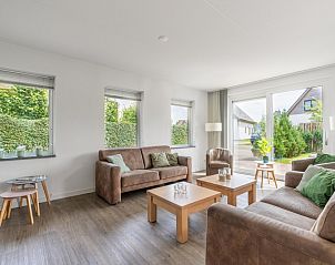 Lichte woonkamer van Bungalowpark 't Hoogelandt - Villa 106F, Texel, met uitzicht op de tuin en comfortabele zithoek.