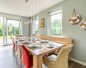 Gezellige eetruimte in Bungalowpark 't Hoogelandt - Villa 106F, Texel, met grote tafel en toegang tot de tuin.