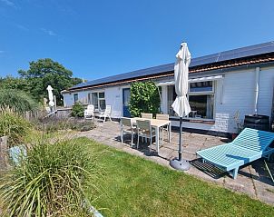 Spacious terrace of Boszicht in De Dennen, Texel with deck chairs and parasol.