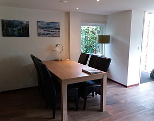 Eetkamer van Bollenveld - de Iris, vakantiehuis in De Dennen, Texel met houten tafel en uitzicht op tuin.