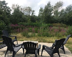 Terras met stoelen bij Vijverhof vakantiewoning in De Dennen, Texel, omgeven door natuur.