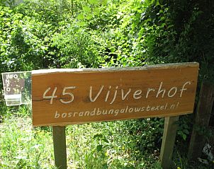 Informatiebord van Vijverhof vakantiehuis in De Dennen, Texel omgeven door groen.