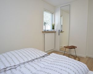 Helles Schlafzimmer mit Spiegel und Aussicht im Bungalowpark 't Luwe Land - Bungalow 13c, De Dennen, Texel, fr eine entspannte Atmosphre.