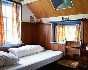 Eenvoudige slaapkamer met houten accenten in Vakantiehuis in Formerum, Terschelling.