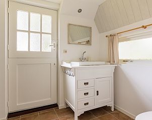 Stijlvolle badkamer in Meiblok vakantiehuis in Formerum, Terschelling met witte wastafel en deur.