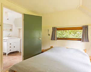 Slaapkamer met tweepersoonsbed in Meiblok vakantiehuis in Formerum, Terschelling met uitzicht op de tuin.