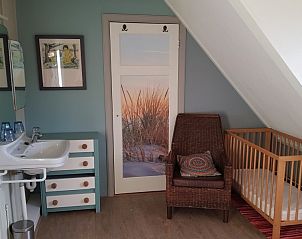 Gezinsvriendelijke kamer in De Sjouw, Hoorn, Terschelling, met wieg en comfortabele stoel.