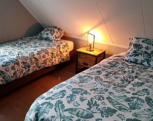 Knusse slaapkamer in De Sjouw, Hoorn, Terschelling, met twee eenpersoonsbedden en sfeerverlichting.