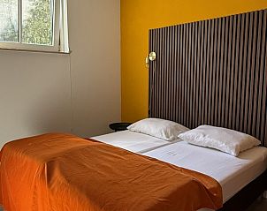 Warme slaapkamer met oranje dekbed in De Hoek vakantiehuis, Hoorn, Terschelling.