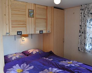 Hoofdslaapkamer in Chalet James, West, Terschelling, met bloemendecor en houten kasten.