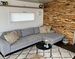 Gezellige woonkamer in Vakantiehuisje in West Terschelling met comfortabele bank en houten accentmuur.