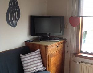 Gezellige woonkamer in BosenDuin vakantiehuis, West aan Zee, Terschelling met tv en houten meubels.