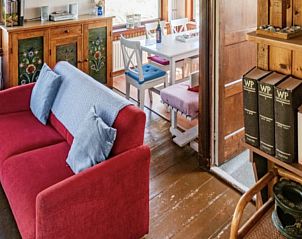 Woonkamer in BosenDuin vakantiehuis, West aan Zee, Terschelling met comfortabele rode bank.