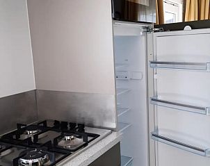 Keuken in WadRust chalet op Terschelling met open koelkast en gasfornuis.