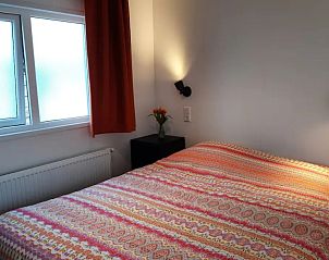 Slaapkamer in WadRust chalet, Midsland Noord, Terschelling met tweepersoonsbed en kleurrijk beddengoed.