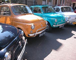 Kleurrijke vintage auto's sieren de straat nabij chalet Hebbes, Midsland Noord, Terschelling, een vleugje nostalgie.