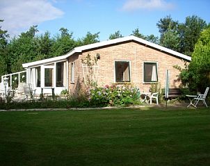 Botter vakantiewoning in Midsland Noord Terschelling omringd door bloemen en tuinmeubilair
