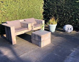 Rustige tuinhoek bij Chalet DOMETO, Midsland Noord, met houten bank en groene haag.