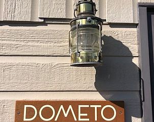 Ingang van Chalet DOMETO, Midsland Noord, met stijlvolle buitenlamp en houten bord.