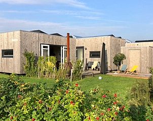 Buitenhuis chalet in Midsland Noord op Terschelling met houten buitenkant en groene tuin.