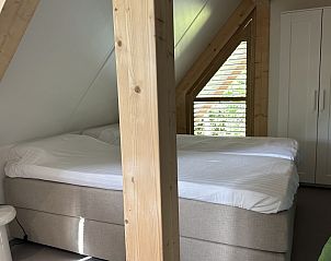 Slaapkamer in Vakantiehuis Schavuit, Midsland Noord, Terschelling, met comfortabel bed en houten accenten.