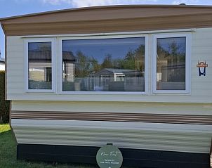 Vooraanzicht van Moai Fuort stacaravan, Midsland Noord, Terschelling met groene omgeving.