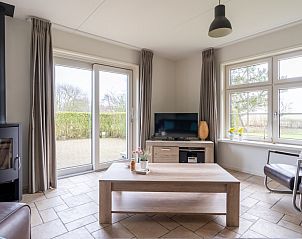 Cozy living room of De Dijkwachter, Ballum, Ameland, with modern furnishings and views of the garden.