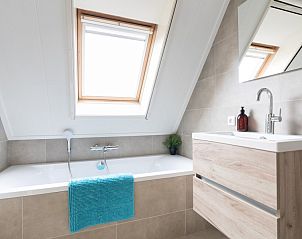 Luxury bathroom in De Dijkwachter, Ballum, Ameland, with bathtub and skylight for natural light.