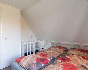 Cozy bedroom with crib in De Dijkwachter, Ballum, Ameland, ideal for families.