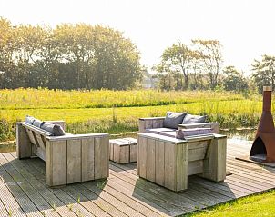Outdoor space with wooden seating in De Dijkwachter, Ballum, Ameland, surrounded by greenery.