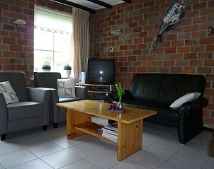 Comfortabele woonkamer in elsbeth.op-ameland vakantiehuis, Ballum, Ameland met moderne meubels en bakstenen muur.