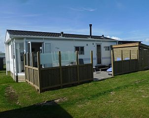 Buitenzijde van Eilandgeluk chalet in Ballum, Ameland met houten omheining en rustige omgeving.