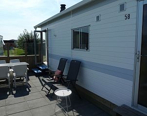 Zonnig terras van Eilandgeluk chalet in Ballum, Ameland met zitgedeelte en uitzicht op natuur.