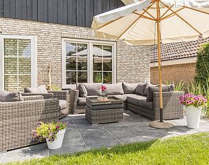 Zonnig terras met parasol bij Chill op Ameland vakantiehuis.
