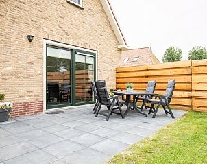 Terras bij Storm Ameland vakantiehuis, Ballum, met buitenmeubilair en omheining.