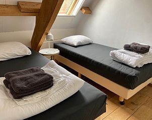 Sfeervolle slaapkamer met twee bedden in appartement Fleurie, Ballum, Ameland, voor een rustgevende nachtrust.