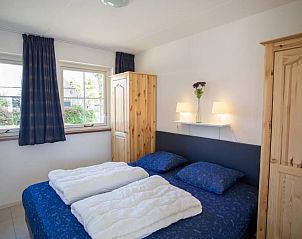 Sfeervolle slaapkamer in Weigelia, Ballum, Ameland met een tweepersoonsbed en warme houten accenten.