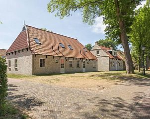 Rustieke buitenkant van vakantiehuis Linde in Ballum, Ameland omgeven door bomen op de Waddeneilanden.