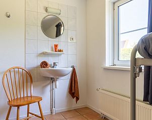 Slaapkamer met wastafel en stoel in Arcoz vakantiehuis, Ballum, Ameland.