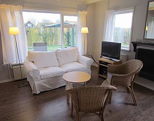 Lichte woonkamer in Calimero vakantiehuis, Ballum, Ameland met uitzicht op de tuin en comfortabele zitplaatsen voor ontspanning.