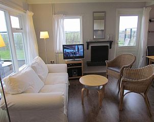 Ruime zitkamer in Calimero vakantiehuis, Ballum, Ameland met moderne inrichting en toegang tot het terras, ideaal voor familieverblijf.