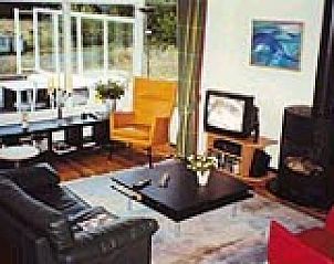 Gezellige woonkamer van De 8e Dag bungalow in Buren, Ameland met comfortabele zithoek en sfeervolle inrichting op de Waddeneilanden.