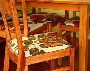 Eetkamerstoelen met bloemenpatroon in Strandjutter G2, chalet in Buren, Ameland, voor een huiselijke sfeer.